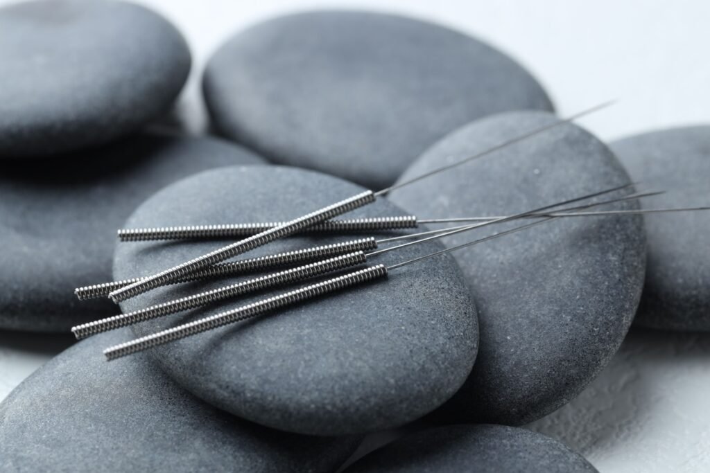 Igły do akupunktury na gładkich szarych kamieniach (zdjęcie poglądowe)